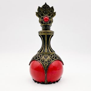 Flacon d'élixir de longue vie rouge avec monture dorée sculptée sur fond blanc.
